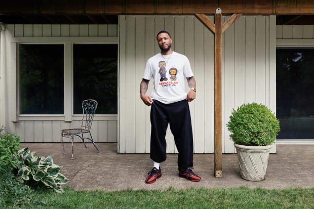 Damian Lillard models his red and black adidas sneakers.