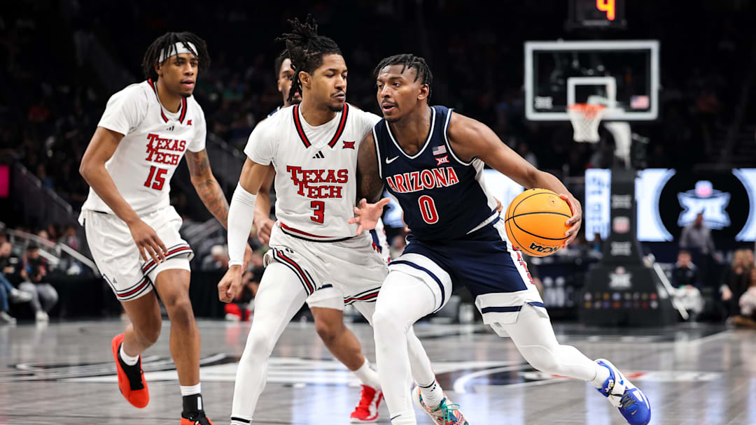 Mar 14, 2025; Kansas City, MO, USA; Arizona Wildcats guard Jaden Bradley (0) drives to the basket around Texas Tech Red Raiders guard Elijah Hawkins (3) during the second half at T-Mobile Center. Mandatory Credit: William Purnell-Imagn Images