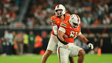 Sep 6, 2025; Miami Gardens, Florida, USA; Miami Hurricanes quarterback Carson Beck (11) helps offensive lineman Francis Mauigoa (61) against the Bethune-Cookman Wildcats during the second quarter at Hard Rock Stadium. Mandatory Credit: Sam Navarro-Imagn Images