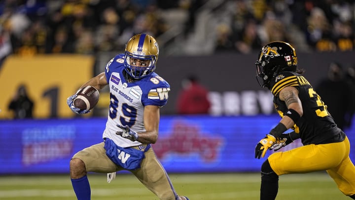 Dec 12, 2021; Hamilton, Ontario, CAN; Winnipeg Blue Bombers wide receiver Kenny Lawler (89) tries to get away from Hamilton Tiger-Cats defensive back Stavros Katsantonis (30) after a pass reception during the first half for the 108th Grey Cup football game at Tim Hortons Field. Mandatory Credit: John E. Sokolowski-USA TODAY Sports