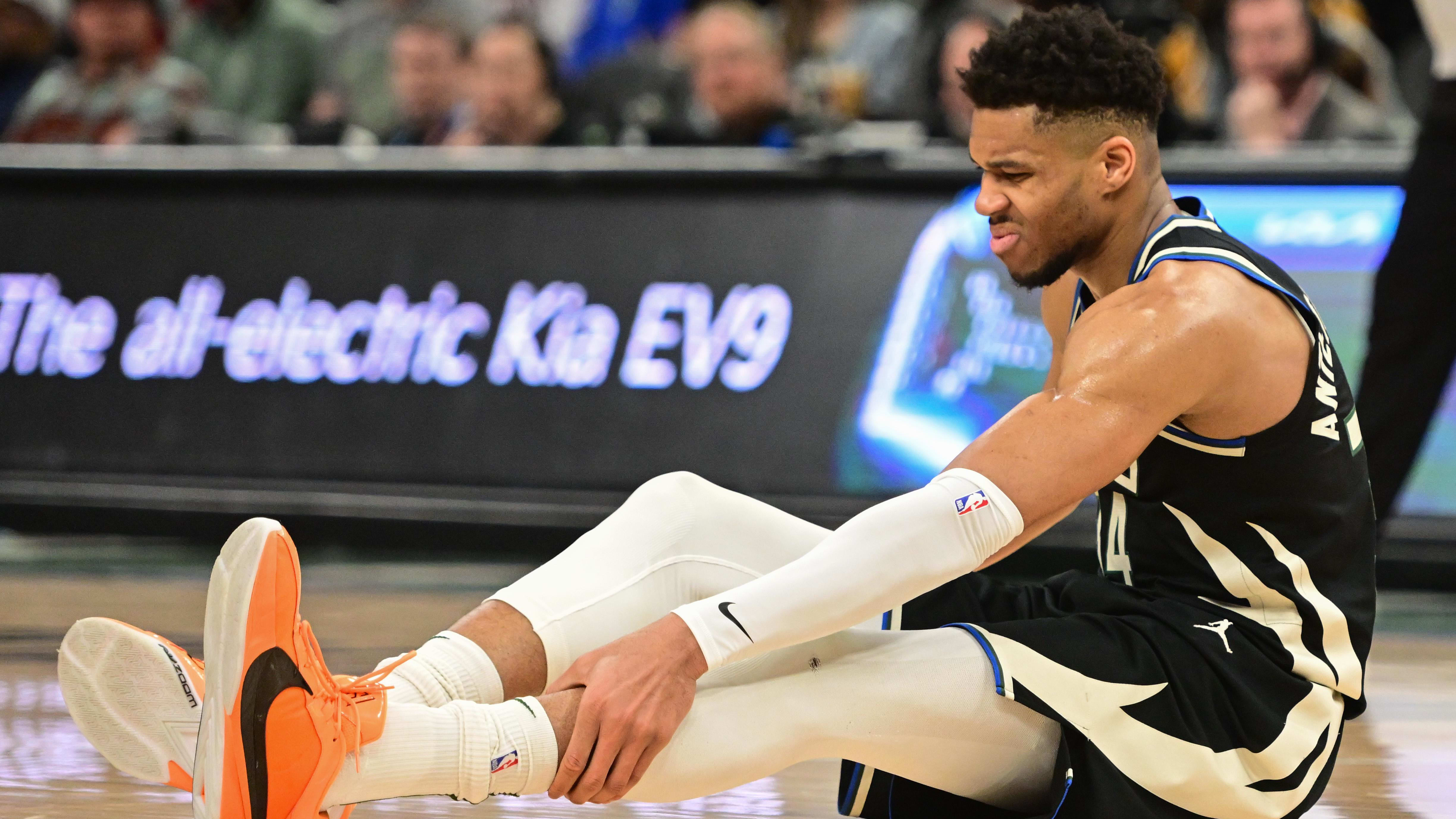 Milwaukee Bucks forward Giannis Antetokounmpo grabs his calf after suffering an injury.