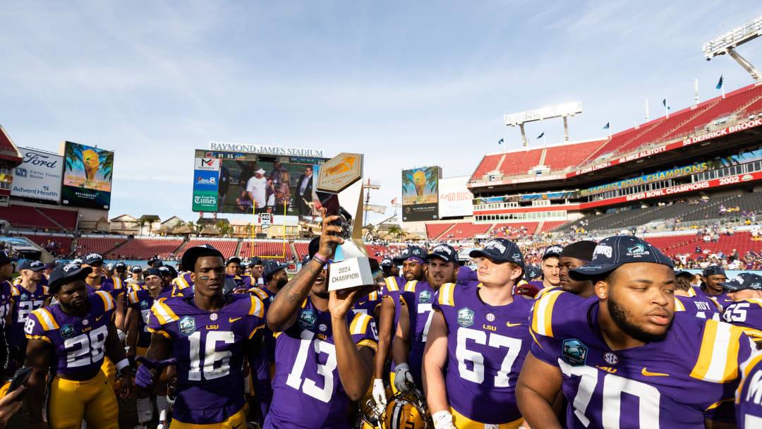 Jan 1, 2024; Tampa, FL, USA; LSU Tigers defensive end Bradyn Swinson (13) and LSU Tigers defensive end Da'Shawn Womack (16) hold up the Reliaquest Bowl championship trophy after the game against the Wisconsin Badgers at the Reliaquest Bowl at Raymond James Stadium. Mandatory Credit: Matt Pendleton-USA TODAY Sports