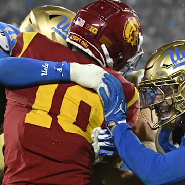 Nov 23, 2024; Pasadena, California, USA; UCLA Bruins defensive back Ramon Henderson (11), linebacker Carson Schwesinger (in back), and linebacker Kain Medrano (20) try to stop USC Trojans wide receiver Kyron Hudson (10) during the fourth quarter at Rose Bowl. Mandatory Credit: Robert Hanashiro-Imagn Images