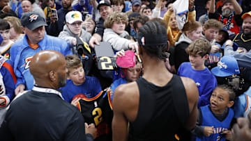 Apr 6, 2025; Oklahoma City, Oklahoma, USA; Basketball fans get autographs from Oklahoma City Thunder guard Shai Gilgeous-Alexander before the start of a game against the Los Angeles Lakers at Paycom Center. Mandatory Credit: Alonzo Adams-Imagn Images