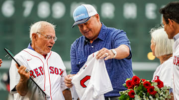 Jul 28, 2022; Boston, Massachusetts, USA; Radio personality Joe Castiglione is handed a shirt by former Red Sox pitcher Roger Clemens during a ceremony honoring him after 40 years as the voice of the Boston Red Sox before the start of the game against the Cleveland Guardians at Fenway Park.