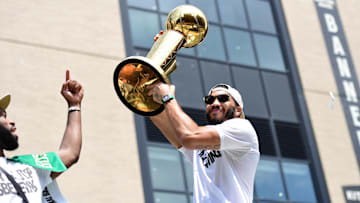 Boston Celtics player Jayson Tatum holds the Larry O'Brien trophy during the Boston Celtics Championship parade.