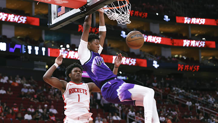 Oct 8, 2025; Houston, Texas, USA; Utah Jazz forward Ace Bailey (19) dunks the ball as Houston Rockets guard Amen Thompson (1) defends during the second quarter at Toyota Center. Mandatory Credit: Troy Taormina-Imagn Images