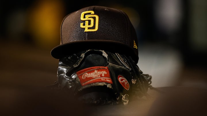 Jun 17, 2022; Denver, Colorado, USA; A detail view of a San Diego Padres hat on a glove in the dugout in the ninth inning against the Colorado Rockies at Coors Field. Mandatory Credit: Isaiah J. Downing-Imagn Images