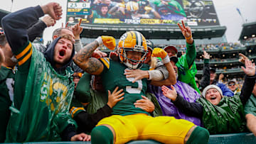 Green Bay Packers wide receiver Christian Watson (9) flexes as he does a “Lambeau Leap” with Packers fans.