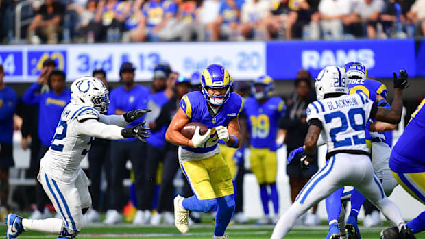 Rams wide receiver Puka Nacua (Blue Uniform) carrying the ball past Colts defensive end Samson Ebukam (White Uniform)