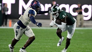 Aug 30, 2024; East Lansing, Michigan, USA;  Michigan State Spartans wide receiver Jaron Glover (4) runs from Florida Atlantic Owls cornerback Logic Hudgens (8) in the third quarter at Spartan Stadium. Mandatory Credit: Dale Young-Imagn Images