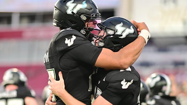 USF freshman quarterback Locklan Hewlett gets a hug from starter Byrum Brown following Hewlett's daring 46-yard touchdown pass off of a fake punt against Boise State.