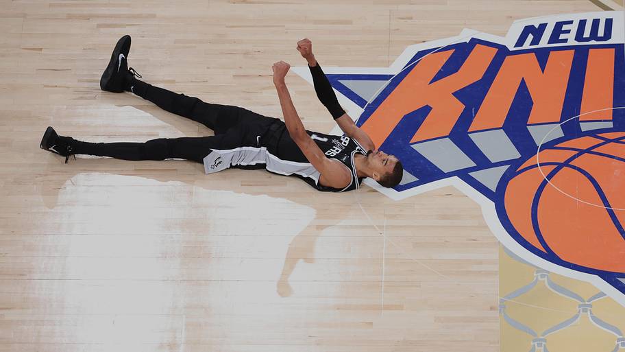 San Antonio Spurs forward Victor Wembanyama lies on the court and reacts against the New York Knicks.
