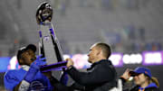 Boise State Broncos safety Seyi Oladipo shares the Mountain West Trophy with head coach Spencer Danielson.
