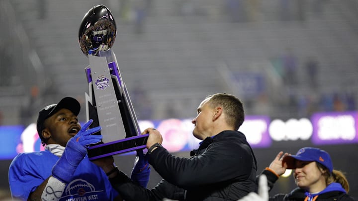 Boise State Broncos safety Seyi Oladipo shares the Mountain West Trophy with head coach Spencer Danielson.