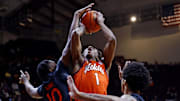 Jan 4, 2025; Blacksburg, Virginia, USA; Miami Hurricanes guard Paul Djobet (10) blocks a shot by Virginia Tech Hokies forward Tobi Lawal (1) during the first half at Cassell Coliseum. Mandatory Credit: Peter Casey-Imagn Images