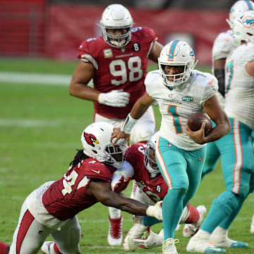 Miami Dolphins quarterback Tua Tagovailoa (1) breaks the tackle of Arizona Cardinals linebacker Markus Golden (44) and Arizona Cardinals cornerback Byron Murphy (33) during the second half at State Farm Stadium in 2020.