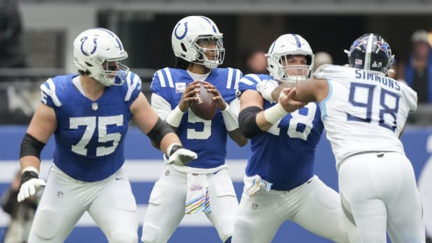 Colts quarterback Anthony Richardson looks to throw the football behind two linemen (blue jersey with white pants/numbers)