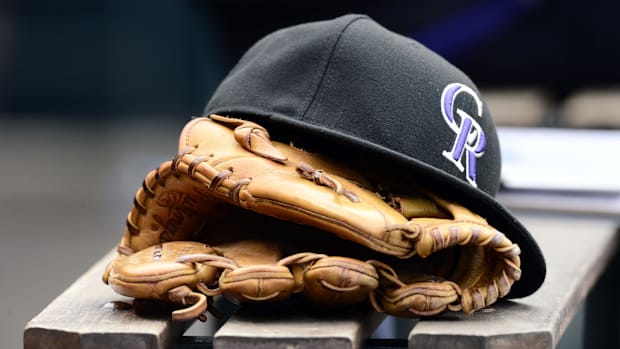 Black Colorado Rockies hat on top of a tan mitt