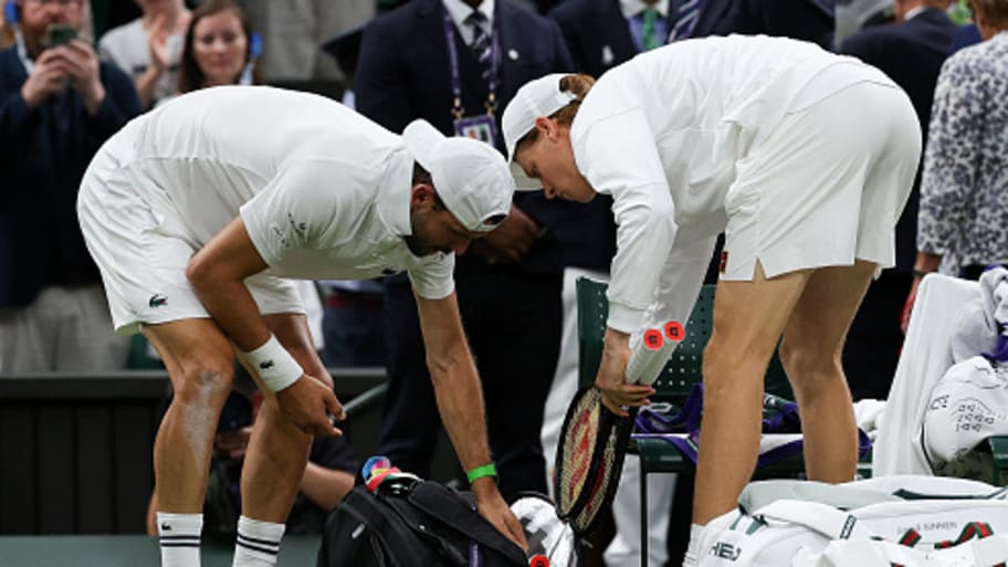 Jannik Sinner helps Grigor Dimitrov pack his things after retiring for a medical issue. | Adrian Dennis/AFP