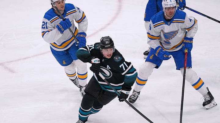 Mar 30, 2026; San Jose, California, USA;  San Jose Sharks center Macklin Celebrini (71) pursues the puck while defended by St. Louis Blues right winger Jimmy Snuggerud (21) and defenseman Justin Holl (4) in the third period at SAP Center at San Jose. Mandatory Credit: David Gonzales-Imagn Images