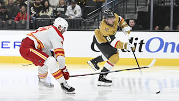 Dec 29, 2024; Las Vegas, Nevada, USA;  Vegas Golden Knights center Jack Eichel (9) shoots the puck past Calgary Flames defenseman Kevin Bahl (7) in the second period of their game at T-Mobile Arena. Mandatory Credit: Candice Ward-Imagn Images
