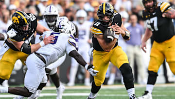 Aug 30, 2025; Iowa City, Iowa, USA; Iowa Hawkeyes quarterback Mark Gronowski (11) clutches the ball as offensive lineman Logan Jones (65) blocks and Albany Great Danes linebacker Ron Holmes (5) looks to make the tackle during the first quarter at Kinnick Stadium. Mandatory Credit: Jeffrey Becker-Imagn Images