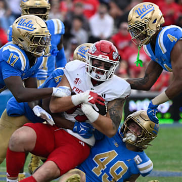 Nov 30, 2024; Pasadena, California, USA; UCLA Bruins linebacker Jalen Woods (17), defensive back Jaylin Davies (6), linebacker Carson Schwesinger (49), and UCLA Bruins defensive back Bryan Addison (4) tackle Fresno State Bulldogs tight end Jake Tarwater (87) during the third quarter at Rose Bowl. Mandatory Credit: Robert Hanashiro-Imagn Images
