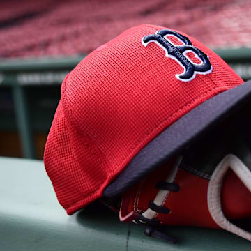 May 18, 2025; Boston, Massachusetts, USA;  A Boston Red Sox hat and glove rests on the railing by the dugout prior to a game against the Atlanta Braves at Fenway Park. Mandatory Credit: Bob DeChiara-Imagn Images