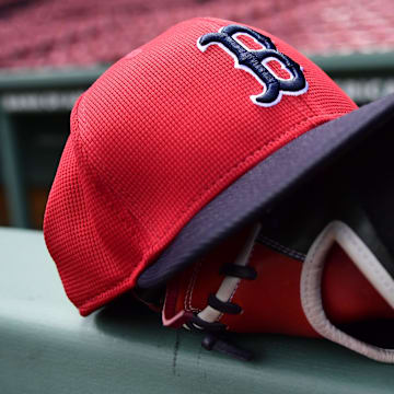 May 18, 2025; Boston, Massachusetts, USA;  A Boston Red Sox hat and glove rests on the railing by the dugout prior to a game against the Atlanta Braves at Fenway Park. Mandatory Credit: Bob DeChiara-Imagn Images