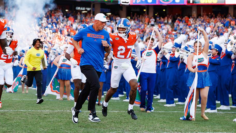 Florida Gators head coach Jon Sumrall and Florida Gators running back Byron Louis run on the field.