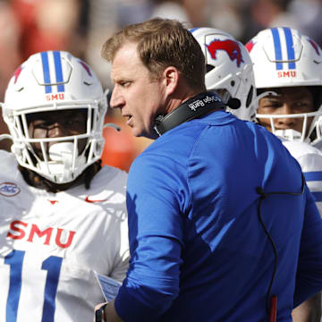 Nov 23, 2024; Charlottesville, Virginia, USA; Southern Methodist Mustangs head coach Rhett Lashlee (center) huddles with players during a stoppage in play in the first half against the Virginia Cavaliers at Scott Stadium. Mandatory Credit: Amber Searls-Imagn Images