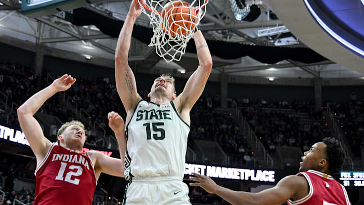 Jan 13, 2026; East Lansing, Michigan, USA;  Michigan State Spartans center Carson Cooper (15) dunks the ball over Indiana Hoosiers forward Tucker Devries (12) and  forward Nick Dorn (7) during the second half at Jack Breslin Student Events Center. Mandatory Credit: Dale Young-Imagn Images