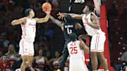 Nov 8, 2025; Houston, Texas, USA; Towson Tigers guard Dylan Williamson (4) shoots the ball as Houston Cougars guard Milos Uzan (7) and center Cedric Lath (8) defend during the first half at Fertitta Center. Mandatory Credit: Troy Taormina-Imagn Images