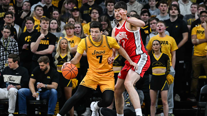 Feb 25, 2026; Iowa City, Iowa, USA; Iowa Hawkeyes forward Alvaro Folgueiras (7) controls the ball as Ohio State Buckeyes center Ivan Njegovan (7) defends during the first half at Carver-Hawkeye Arena. Mandatory Credit: Jeffrey Becker-Imagn Images