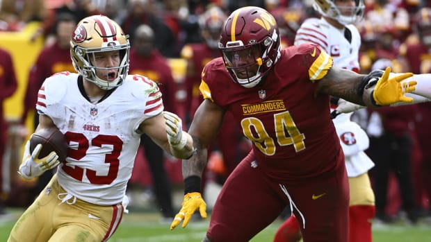  Christian McCaffrey (23) carries the ball as Washington Commanders defensive tackle Daron Payne 