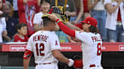 Angels center fielder Brett Phillips (8) places a samurai warrior hat on right fielder Hunter Renfroe (12) as Renfroe reaches the dugout after hitting a solo home run against the Kansas City Royals in the fourth inning at Angel Stadium on April 22, 2023.