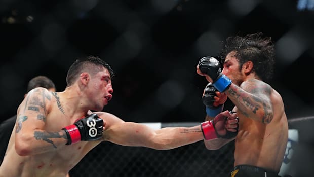 Brandon Moreno (red gloves) fights Alexandre Pantoja (blue gloves) during UFC 290 at T-Mobile Arena. 