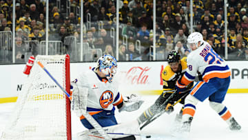 Jan 5, 2025; Boston, Massachusetts, USA; Boston Bruins right wing David Pastrnak (88) redirects the puck past New York Islanders goaltender Ilya Sorokin (30) while defenseman Alexander Romanov (28) defends during the third period at TD Garden. Mandatory Credit: Bob DeChiara-Imagn Images