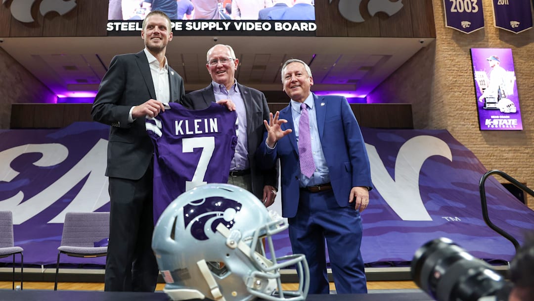 Dec 5, 2025; Manhattan, Kansas, USA; Collin Klein, athletic director Gene Taylor and K-Statae President Richard Litton hold a jersey after Klein was named the new head coach of the Kansas State Wildcats football team at Morgan Family Arena. Mandatory Credit: Scott Sewell-Imagn Images