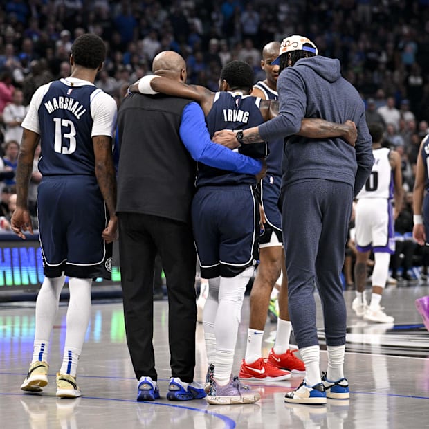 Dallas Mavericks goalkeeper Kyrie Irving (11) is helped out of the field 