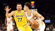 Oct 14, 2025; Phoenix, Arizona, USA; Phoenix Suns guard Koby Brea (14) drives to the basket against Los Angeles Lakers guard Luka Doncic (77) during an NBA preseason game at Mortgage Matchup Center. Mandatory Credit: Mark J. Rebilas-Imagn Images