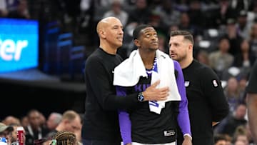 Dec 30, 2024; Sacramento, California, USA; Sacramento Kings guard De'Aaron Fox (center) stands on the sideline with interim head coach Doug Christie (left) and assistant coach Luke Loucks (right) during the fourth quarter against the Dallas Mavericks at Golden 1 Center. Mandatory Credit: Darren Yamashita-Imagn Images
