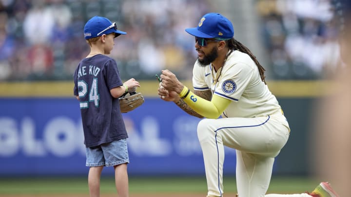 Seattle Mariners shortstop J.P. Crawford (3) with a small child on the field before the game against the Houston Astros at T-Mobile Park in 2024.