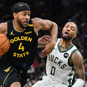 Feb 10, 2025; Milwaukee, Wisconsin, USA;  Golden State Warriors forward Moses Moody (4) drives for the basket against Milwaukee Bucks guard Damian Lillard (0) in the second quarter at Fiserv Forum. Mandatory Credit: Benny Sieu-Imagn Images