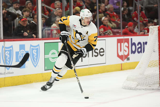 Hockey player in white uniform skates with the puc