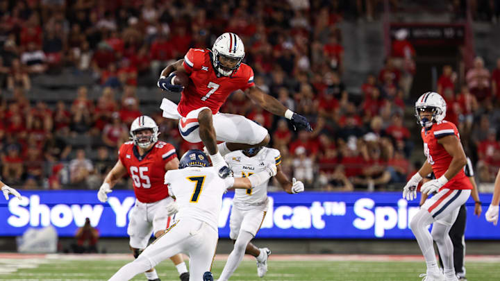 Sep 7, 2024; Tucson, Arizona, USA; Arizona Wildcats running back Quali Conley (7) jumps over Northern Arizona Lumberjacks cornerback Demetrius Freeney (7) during the second quarter at Arizona Stadium. Mandatory Credit: Aryanna Frank-Imagn Images