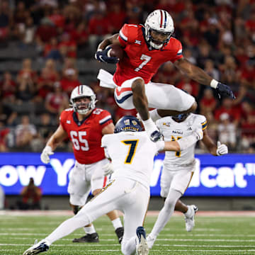 Sep 7, 2024; Tucson, Arizona, USA; Arizona Wildcats running back Quali Conley (7) jumps over Northern Arizona Lumberjacks cornerback Demetrius Freeney (7) during the second quarter at Arizona Stadium. 