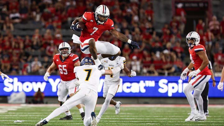 Sep 7, 2024; Tucson, Arizona, USA; Arizona Wildcats running back Quali Conley (7) jumps over Northern Arizona Lumberjacks cornerback Demetrius Freeney (7) during the second quarter at Arizona Stadium. 