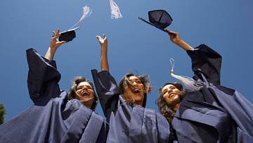 Three female graduate students throwing mortar boards
